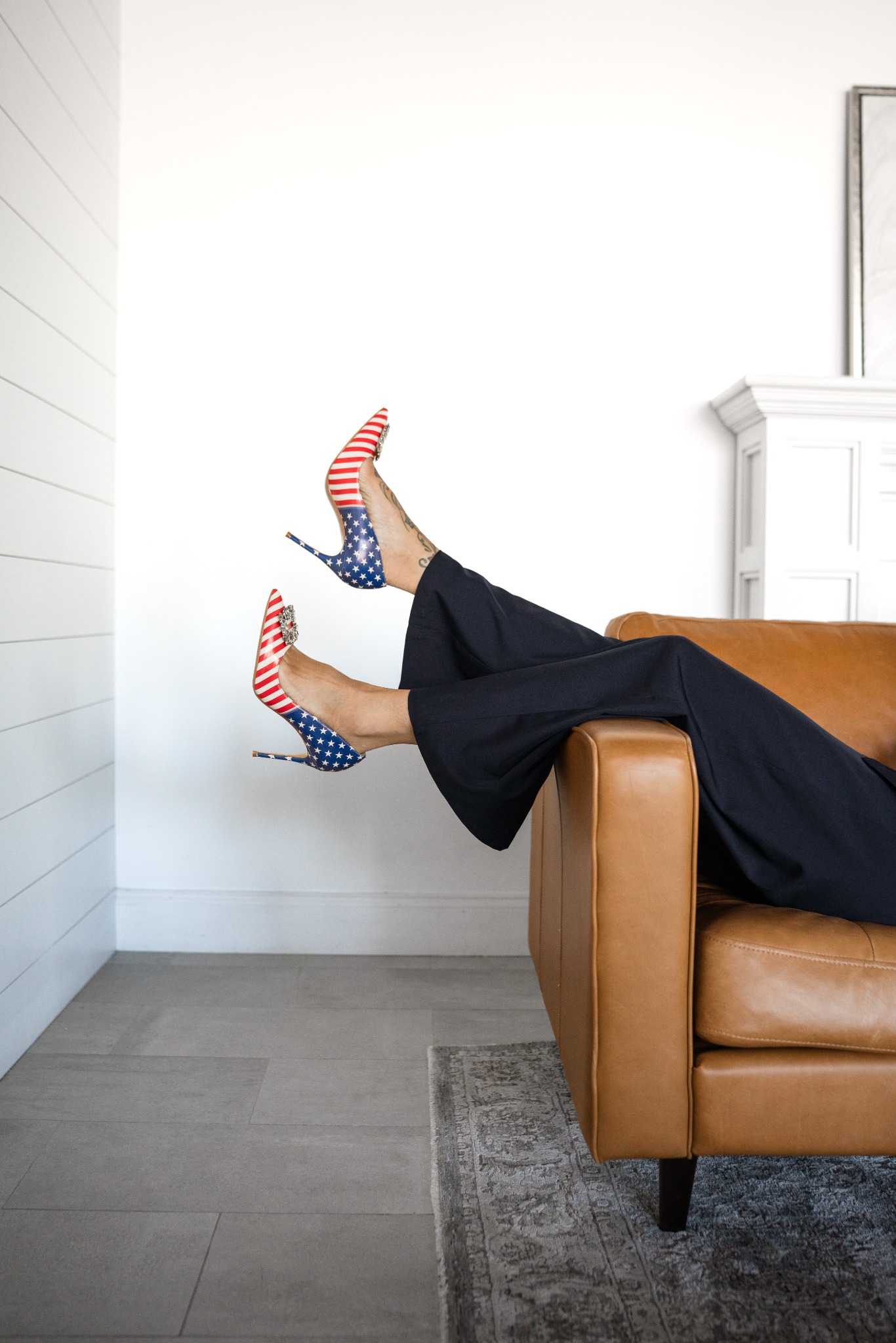 Jennifer’s patriotic stars-and-stripes heels resting on a caramel chair
